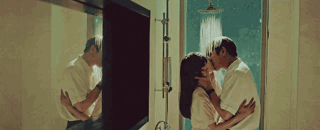 a man and a woman are kissing under a shower head
