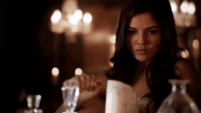 a woman sitting at a table with a candle and a glass