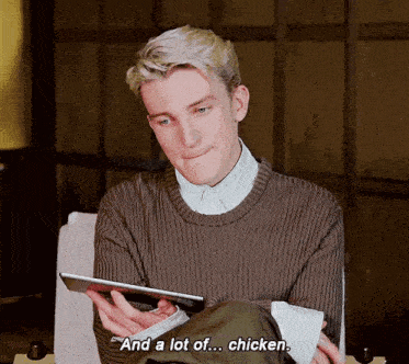 a man is sitting in a chair holding a tablet and saying and a lot of ... chicken .
