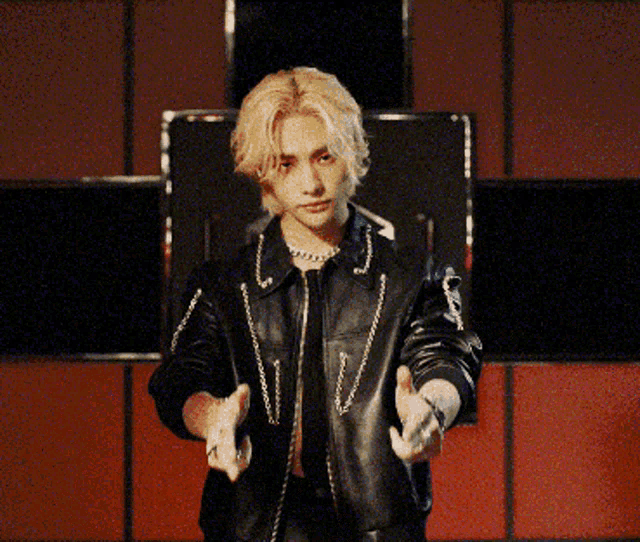 a man in a black leather jacket is pointing his fingers at the camera
