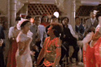 a group of people are dancing in a room including a man with a gun on his arm