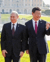 two men in suits and ties are standing next to each other on a lush green field .