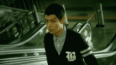 a young man is standing in front of an escalator .