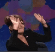 a woman in a black jacket holds her hands up in the air