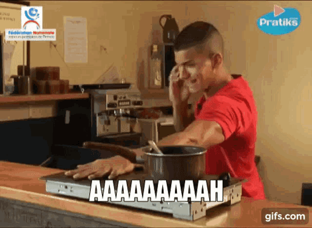 a man in a red shirt is talking on a cell phone while preparing food