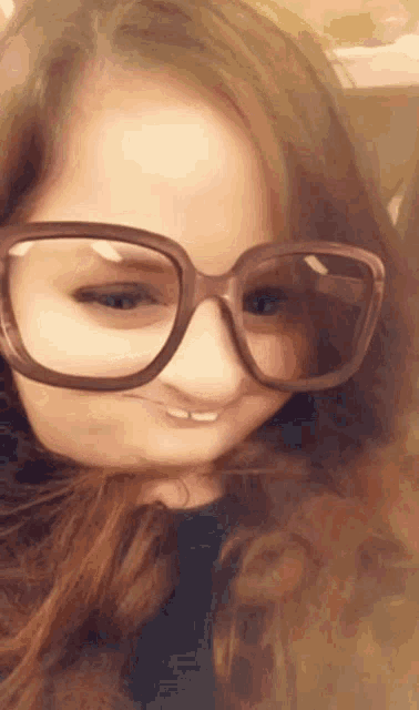 a girl wearing glasses making a face with her hair