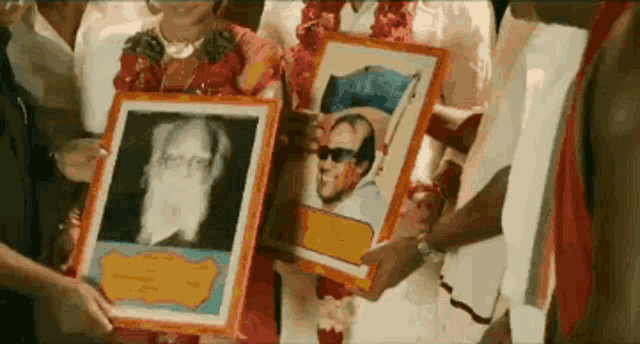a group of people holding framed pictures of a man with a beard