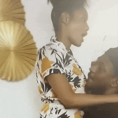 a woman in a floral dress is holding a man in her arms and looking at him .