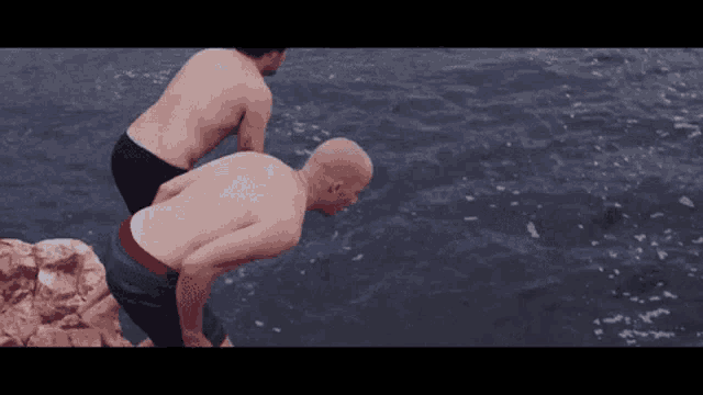 two shirtless men are standing in the water