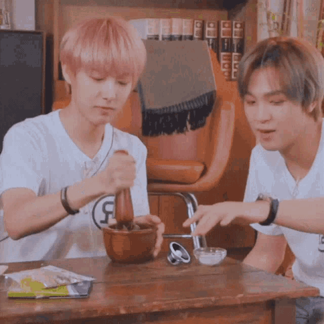 two young men are sitting at a table and one of them has the letter r on their shirt