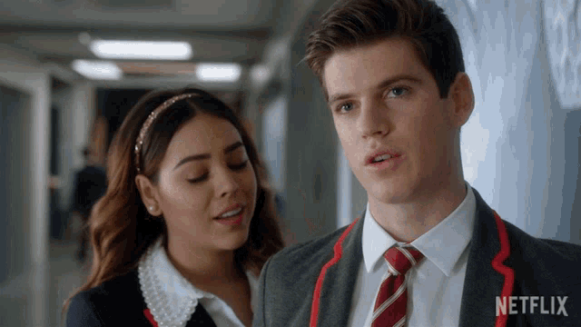 a man in a suit and tie stands next to a woman in a headband with the word netflix on the bottom