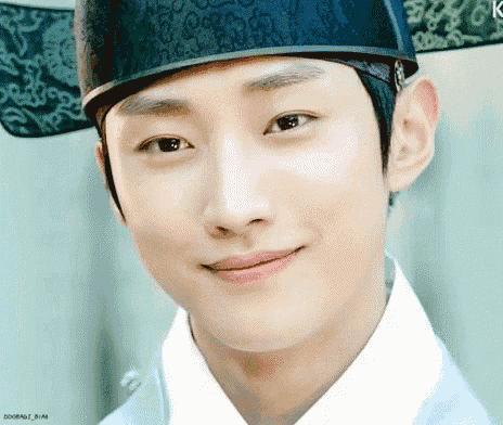 a young man wearing a hat and a white shirt is smiling .