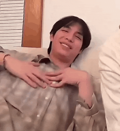a man is sitting on a couch with his hands on his chest .