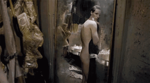 a naked man is standing in front of a mirror looking at himself .