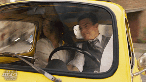a man and a woman are sitting in a yellow car with the numbers m1-7 on the side