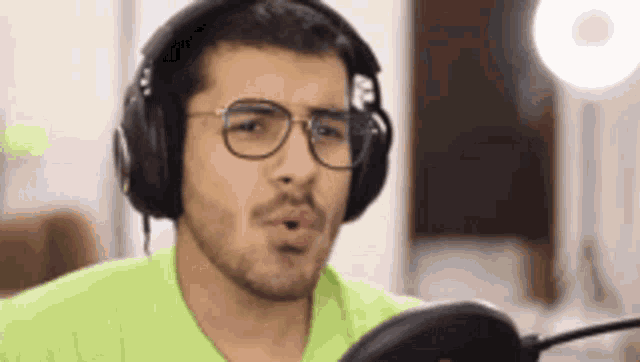 a man with glasses and headphones is singing into a microphone .