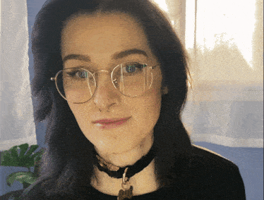 a woman wearing glasses and a black choker
