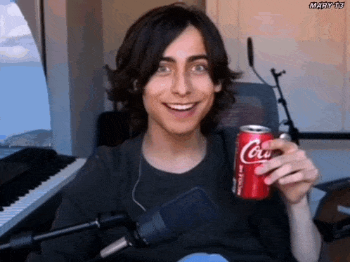 a young man is smiling while holding a can of coca cola .
