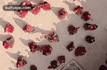 a group of people are standing around a table with a bunch of red objects on it .