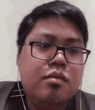 a close up of a man wearing glasses and ear buds .