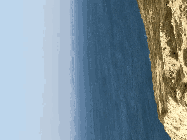 a cliff overlooking a body of water with a blue sky in the background