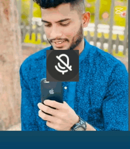 a man in a blue shirt is holding a cell phone with a microphone on it .