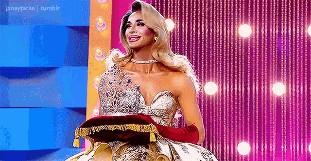 a drag queen is holding a pillow on a stage .