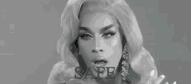a black and white photo of a drag queen with the words `` safe '' written in green .