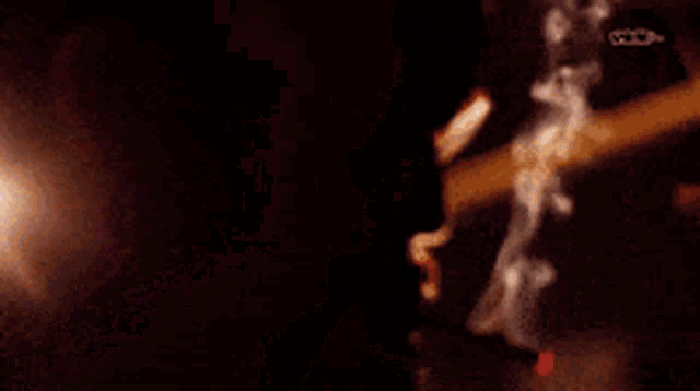 smoke is coming out of a person 's mouth in a dark room .
