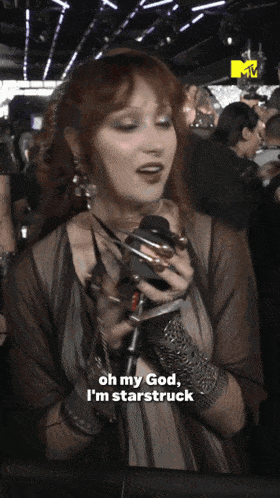 a woman is holding a microphone and says oh my god i 'm starstruck