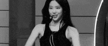 a black and white photo of a woman wearing a black tank top .