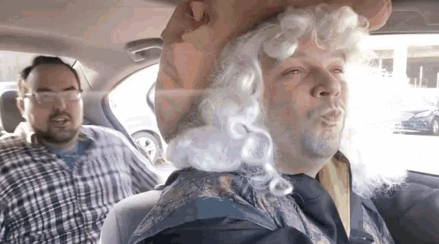 a man wearing a wig and glasses is sitting in a car .