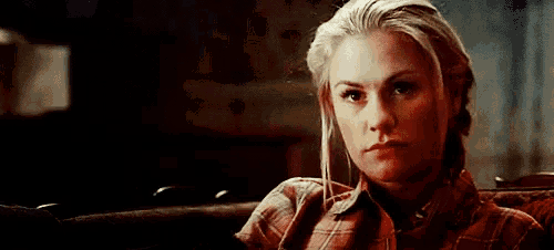 a woman is sitting on a couch wearing a plaid shirt .