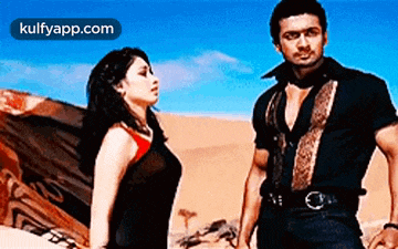 a man and a woman standing next to each other in the desert holding hands .