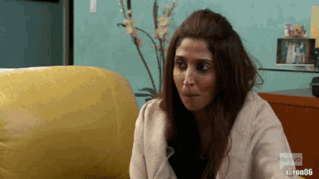 a woman sitting on a yellow couch with bravo written on the bottom