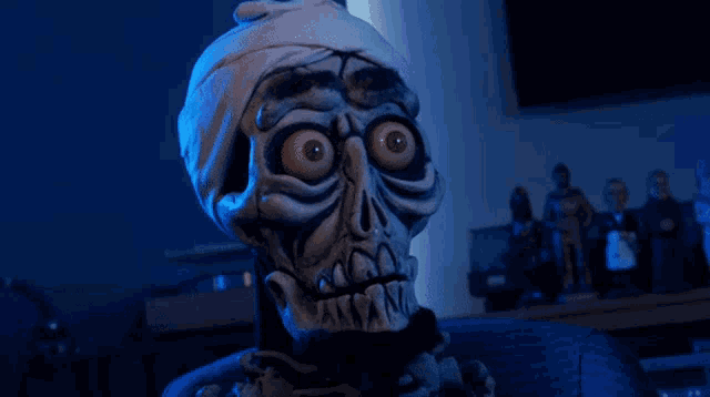 a skeleton with a bandage on its head is sitting in a dark room