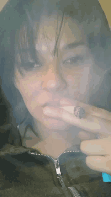 a woman smoking a cigarette with a zipper on her jacket visible