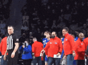 a referee stands in front of a group of people wearing red shirts that say ' ucsd ' on them