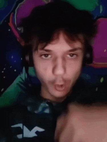 a young man is making a funny face while wearing headphones and a hurley shirt .