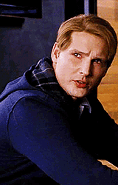 a man with blonde hair is wearing a blue sweater