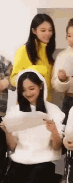 a woman in a yellow sweater is sitting next to a woman in a white sweater .