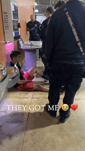 a group of people standing around a man laying on the floor with the words they got me below him