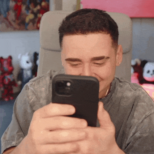 a man is smiling while looking at a cell phone