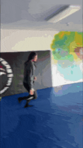 a blurry picture of a person running on a blue mat in a gym