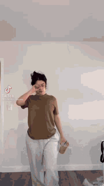 a woman wearing a brown t-shirt and white shorts is holding a drink .