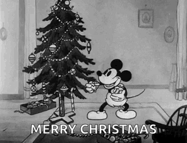 mickey mouse is decorating a christmas tree in a living room .