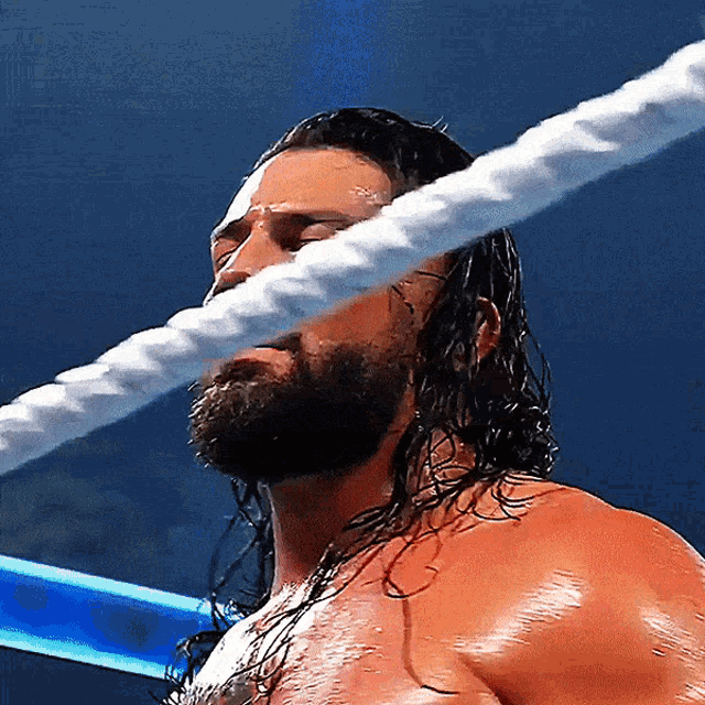a man with long hair and a beard is standing in a wrestling ring