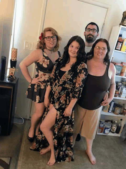 a group of people posing for a picture including a woman in a floral dress and a man with glasses