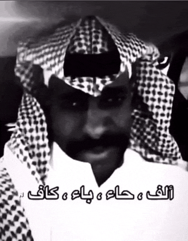 a black and white photo of a man wearing a head scarf with arabic writing on it