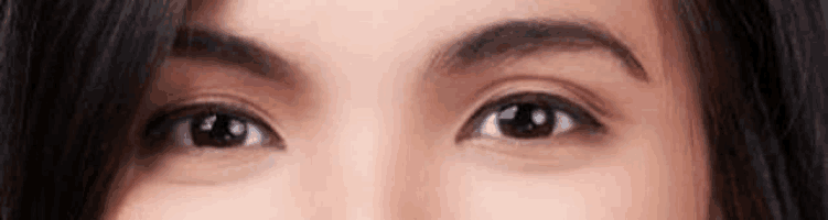 a close up of a woman 's eyes with a slight smile on her face .